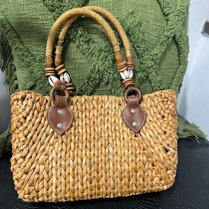 Woven handbag with decorative shell and bead handles.